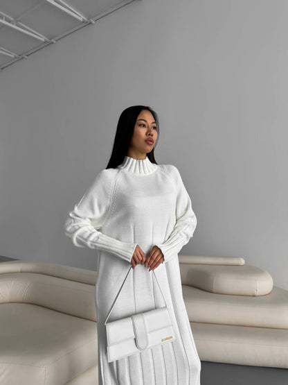Woman in a white outfit holding a handbag in a minimalistic setting
