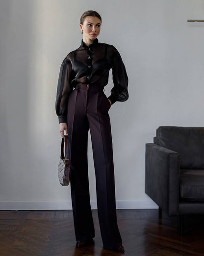 Woman wearing a black blouse and dark pants in an indoor setting.