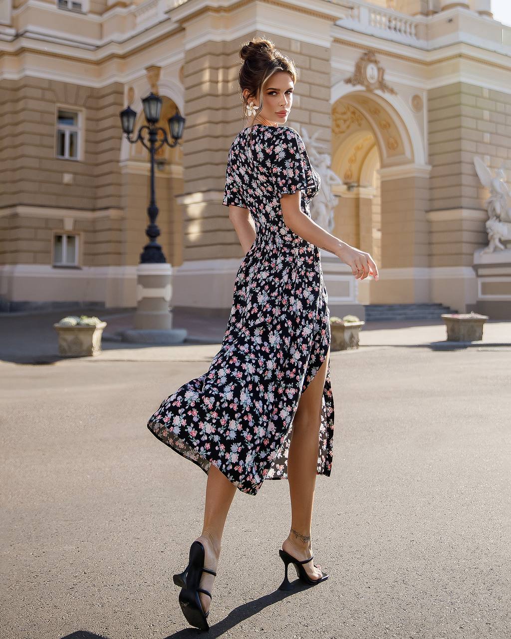 Woman in a floral dress walking in front of an elegant building