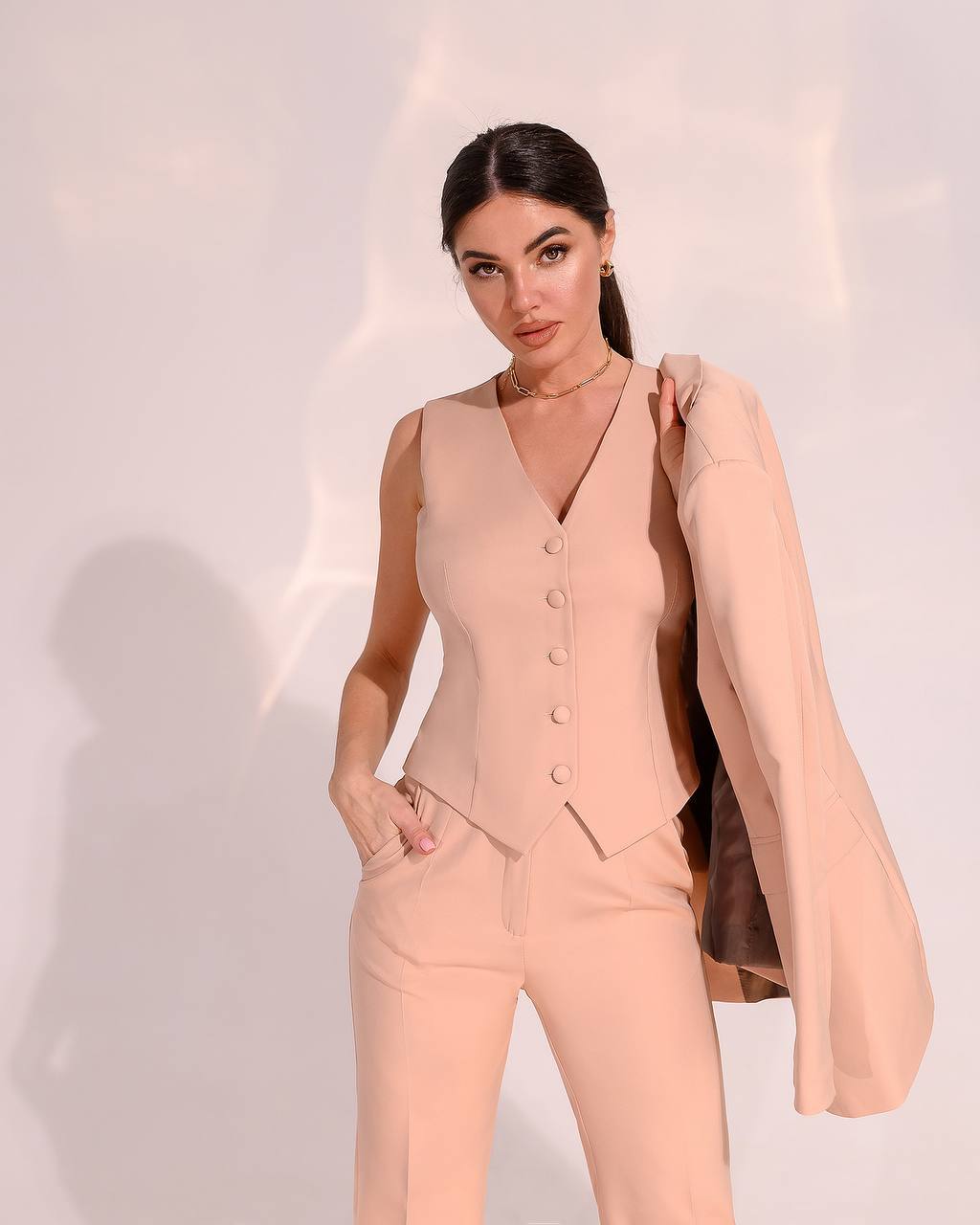 Woman wearing a peach suit with a plain background