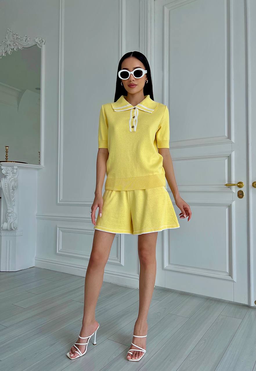 Woman in a yellow outfit standing in a room with white walls and a door.