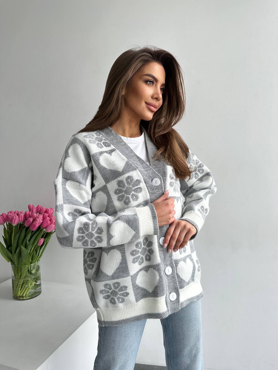 Woman wearing a patterned cardigan with flowers on a gray background