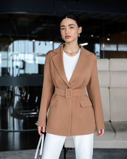 Woman wearing a brown blazer over a white top in an indoor setting