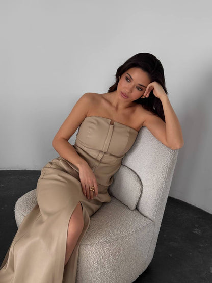 Woman in a strapless beige dress sitting on a textured chair against a plain background