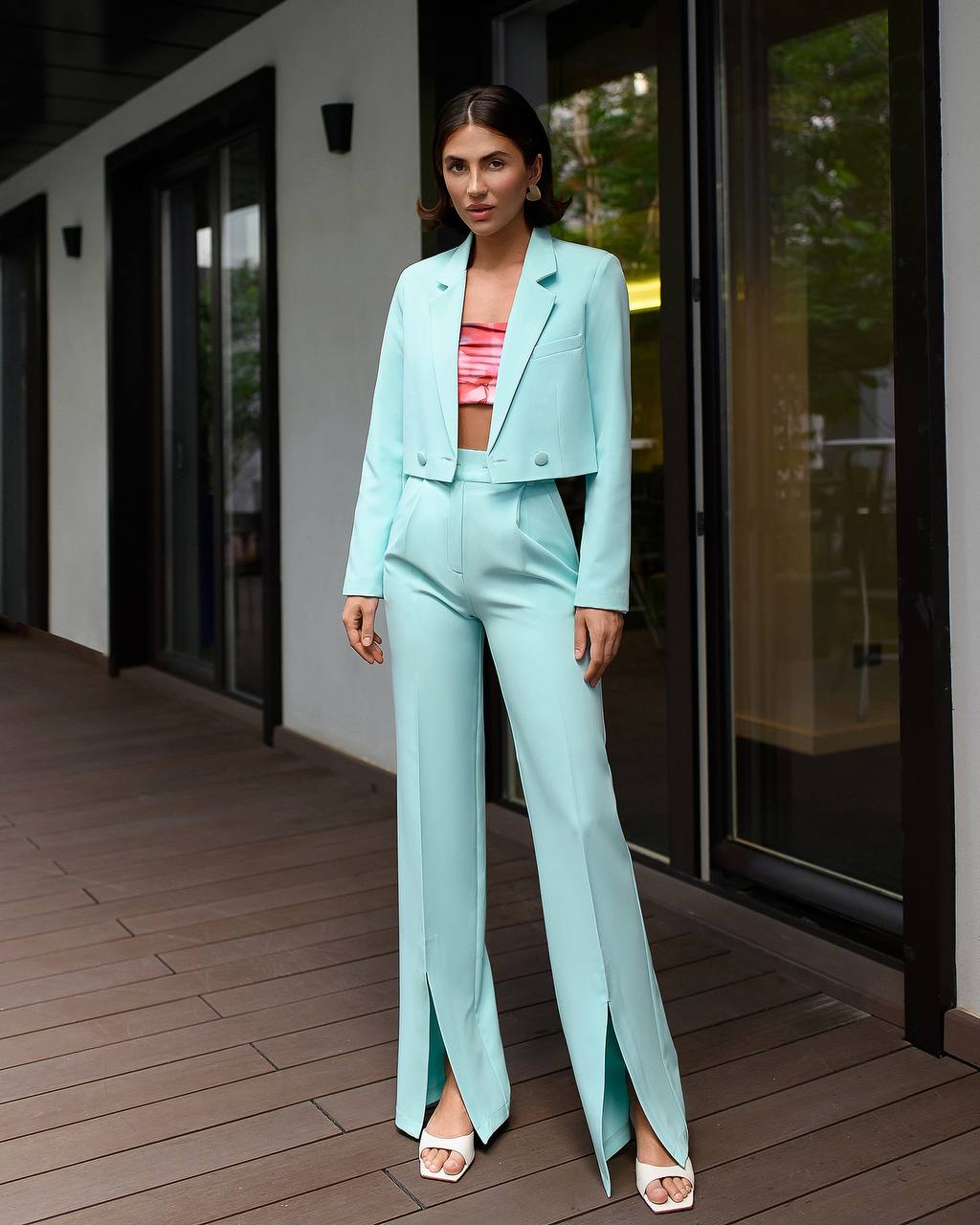 Woman in a light blue suit standing on a wooden deck.