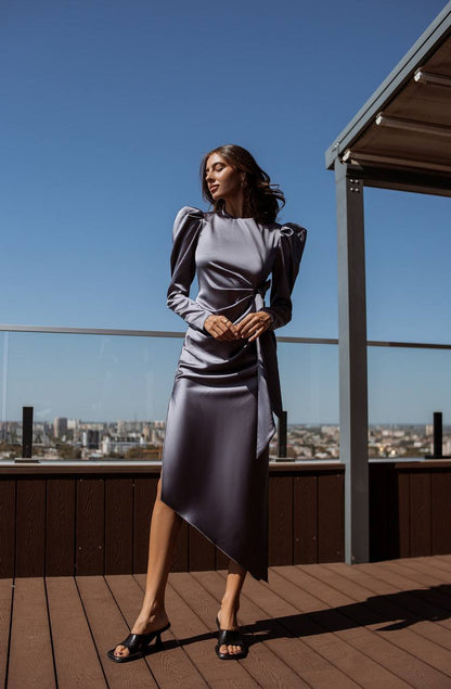 Woman in a gray dress standing on a rooftop with a cityscape view