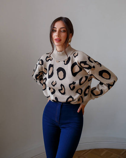 Woman wearing a leopard print sweater and blue pants against a plain background