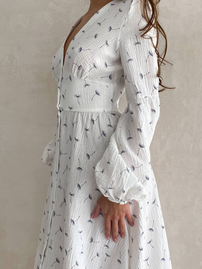 White dress with black floral pattern worn by a person against a neutral background