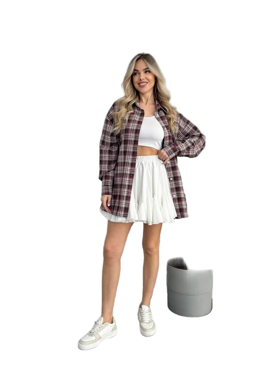 Woman wearing a plaid shirt, white top, and skirt with a white background