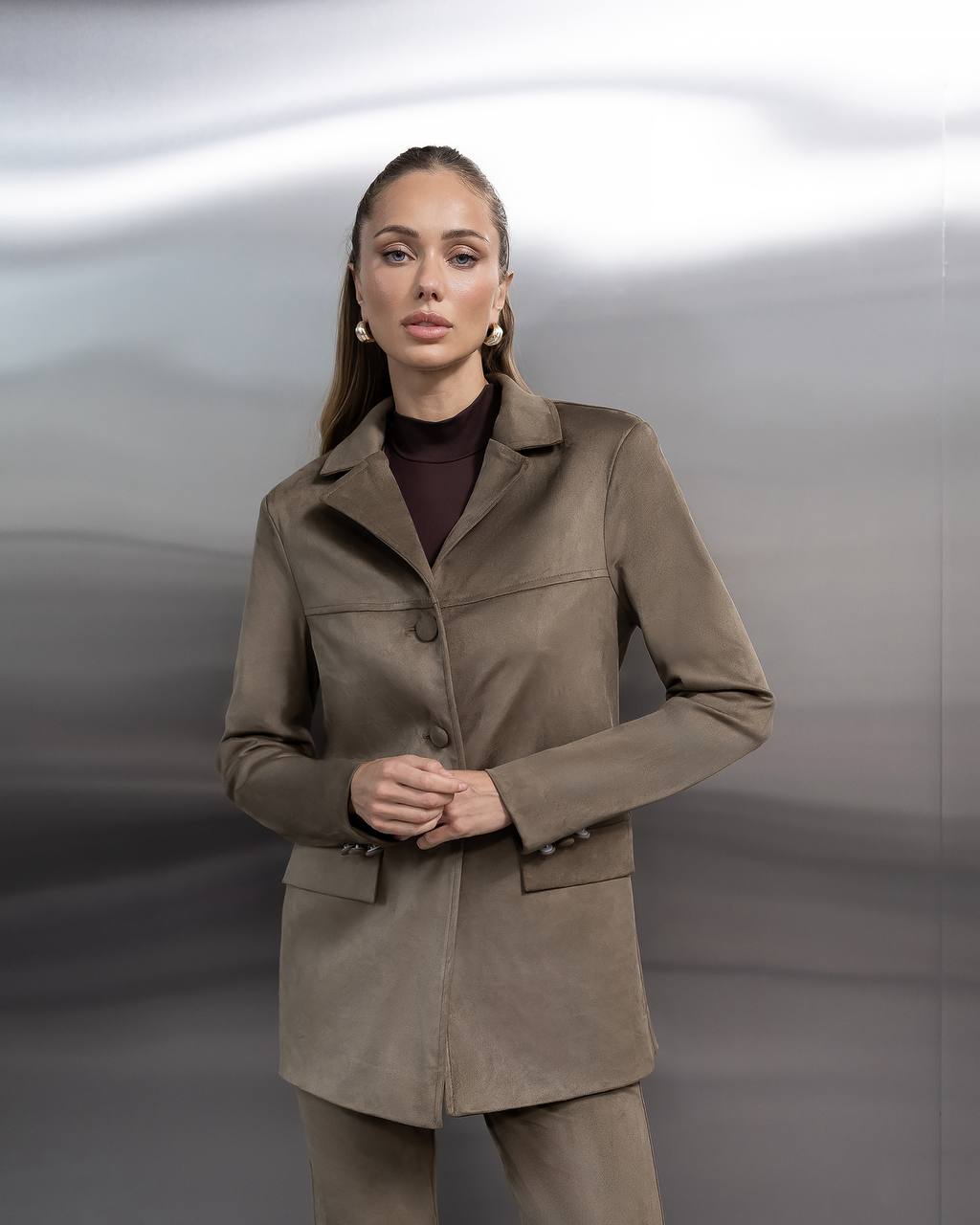 Woman wearing a brown coat against a neutral background