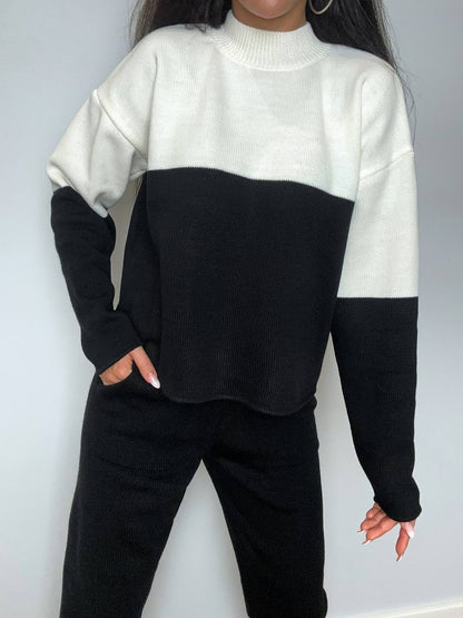 Person wearing a black and white color-blocked sweater against a plain background