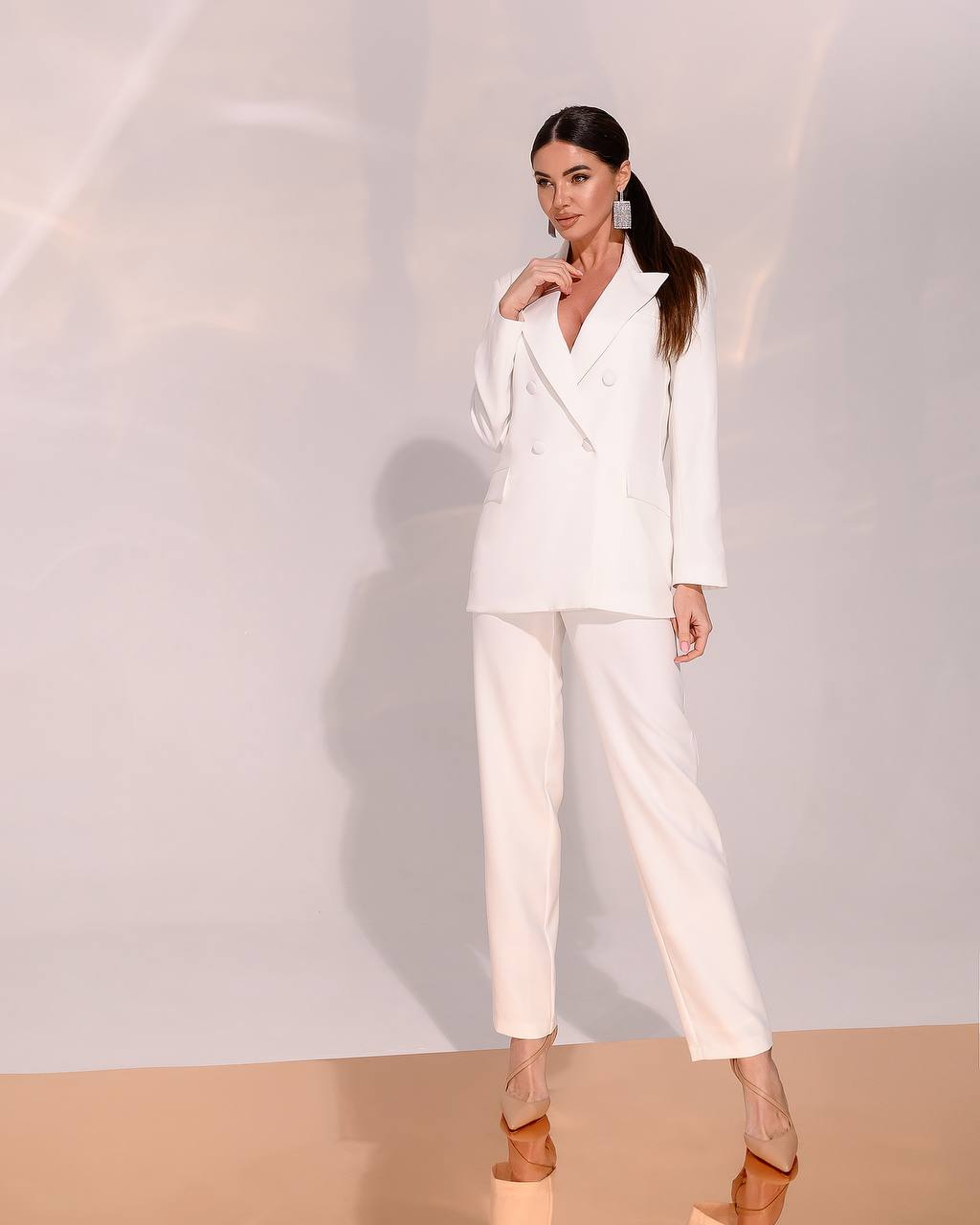 Woman wearing a white suit against a plain background