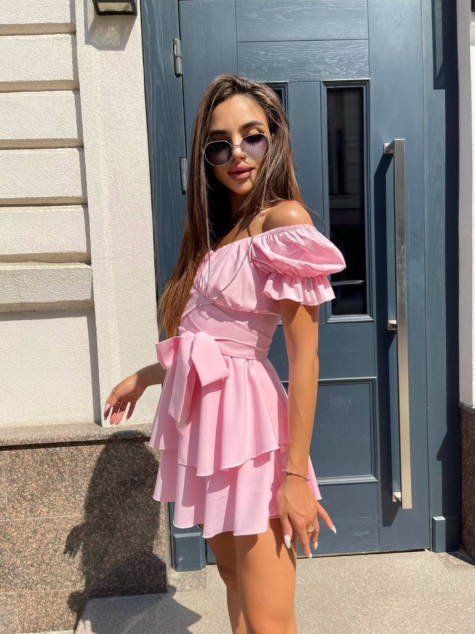 Woman in a pink dress standing in front of a blue door.