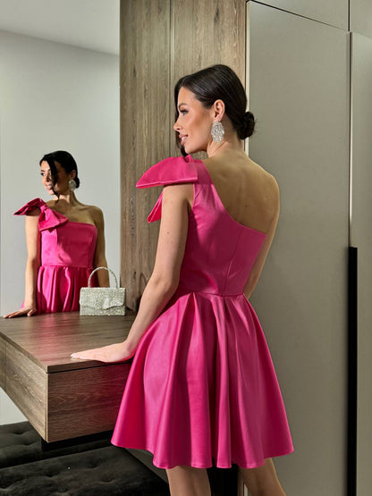 Woman in a pink dress looking at herself in a mirror.