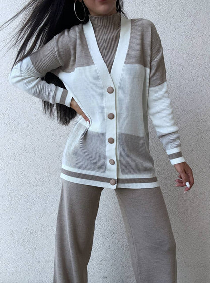 Person wearing a two-tone cardigan with gray and white colors against a plain background