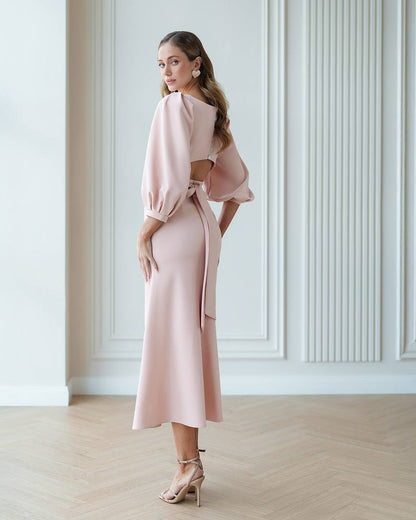 Woman wearing a pink outfit in a room with white walls and wooden floor.