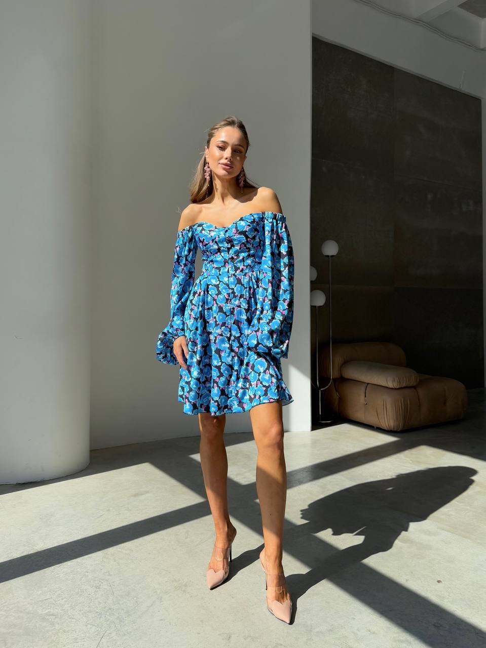 Woman wearing a blue floral off-shoulder dress in a modern indoor setting