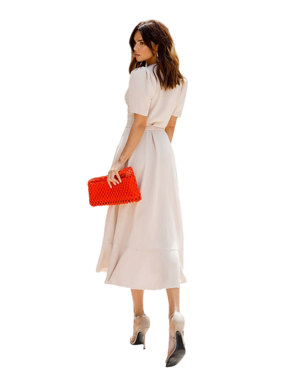 Woman in a white dress holding a red clutch on a white background