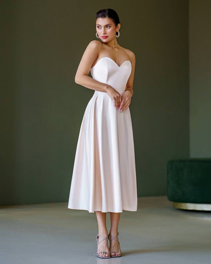 Woman wearing a strapless white dress against a plain background