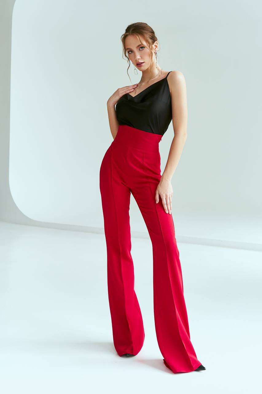 Woman wearing a black top and red pants on a white background