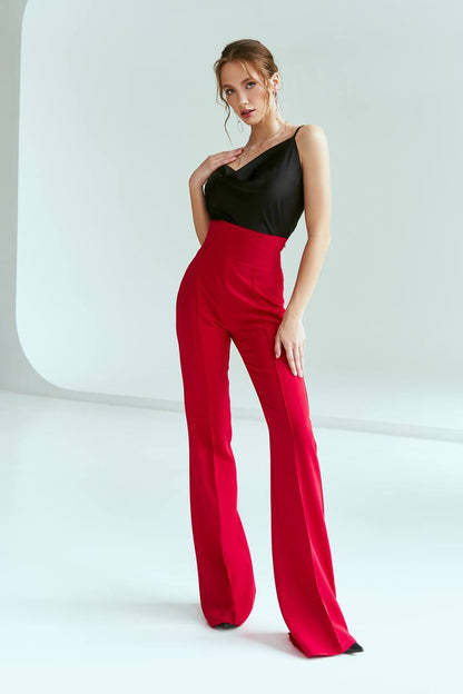 Woman wearing a black top and red pants on a white background