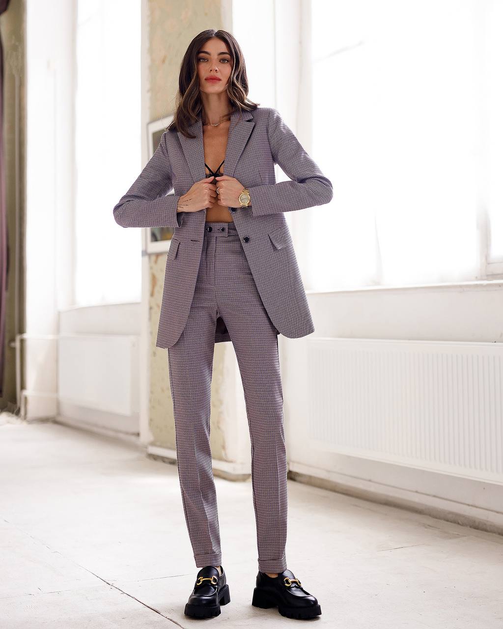 Woman wearing a gray checkered suit in a bright room.