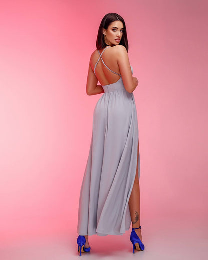 Woman in a light blue dress with a high slit on a pink background