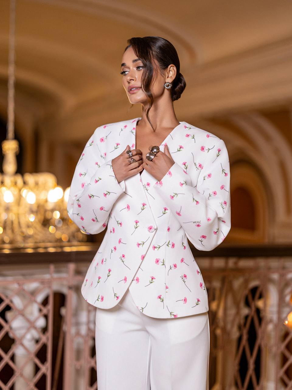 Woman wearing a white floral blazer in an elegant indoor setting