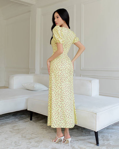 Woman in a yellow floral dress standing in a modern room with white furniture.