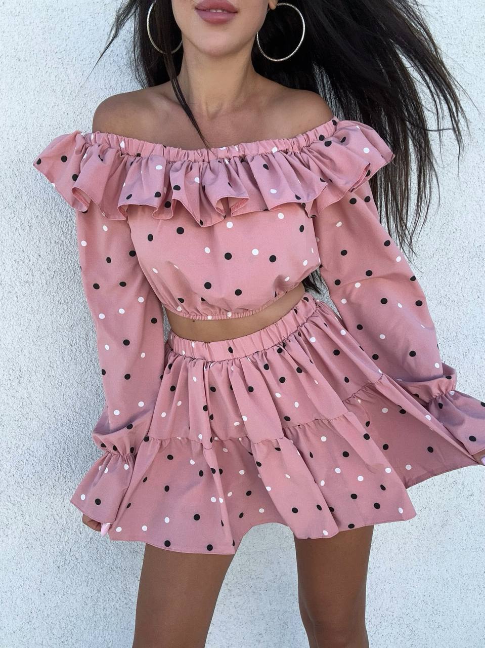 Pink polka dot off-shoulder top and skirt set on a plain background