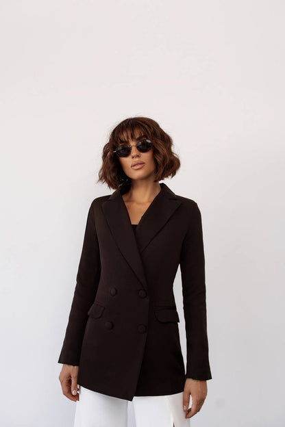 Woman wearing a black blazer and sunglasses against a white background