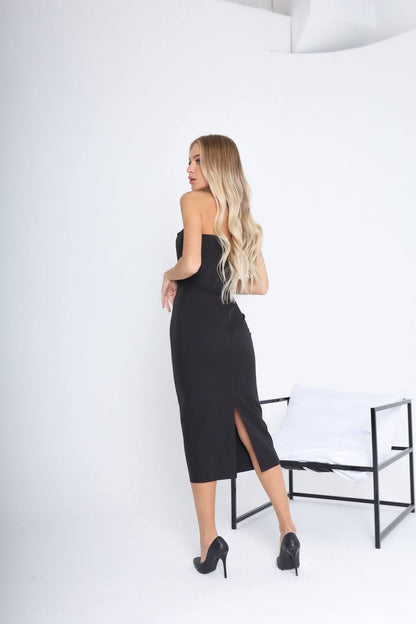 Woman in a black strapless dress standing against a white background