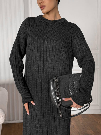 Woman wearing a black ribbed sweater and holding a black clutch.
