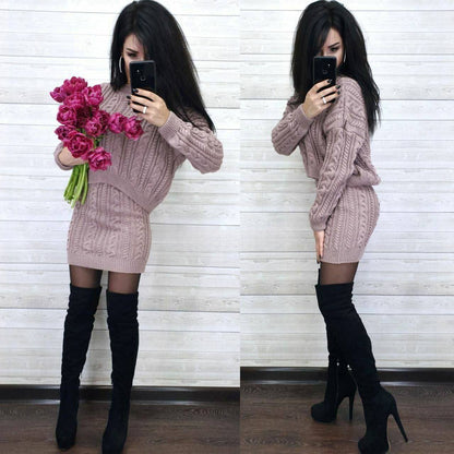 Woman in a pink cable knit dress with black knee-high boots holding pink flowers, taking a mirror selfie.