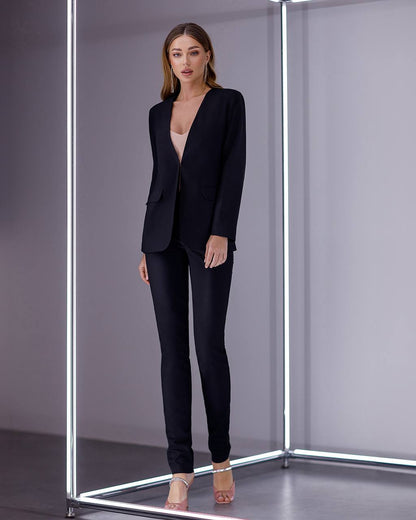 Woman wearing a black suit standing inside a reflective, metallic box.