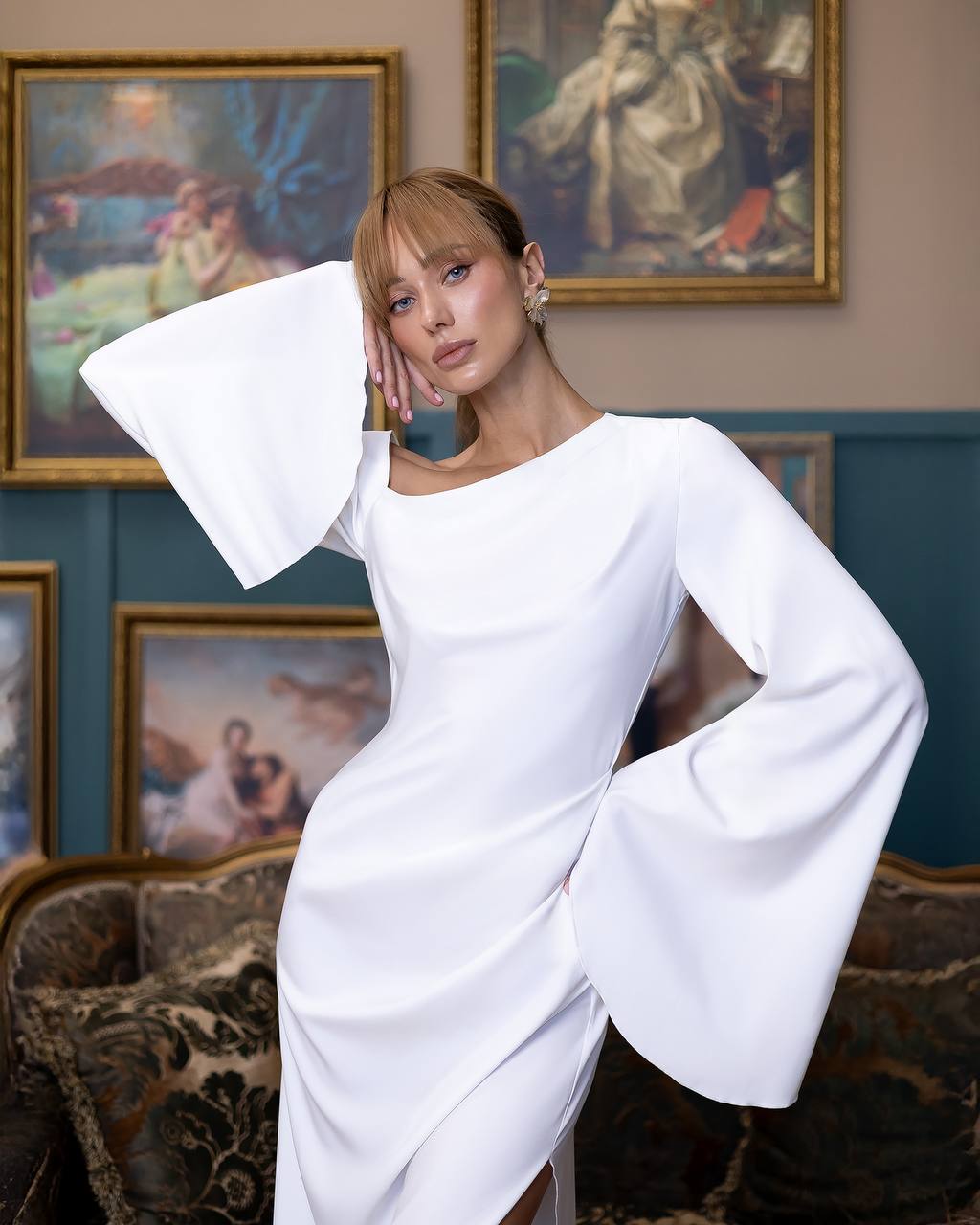 Woman in a white dress with wide sleeves in an art gallery setting