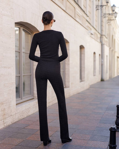 Person wearing a black outfit standing on a sidewalk with a building in the background