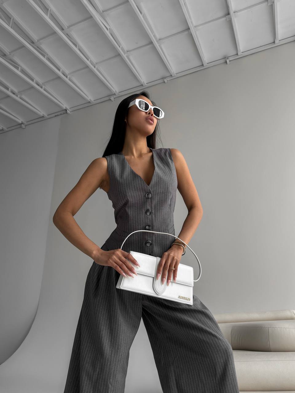 Woman holding a white handbag in a modern indoor setting