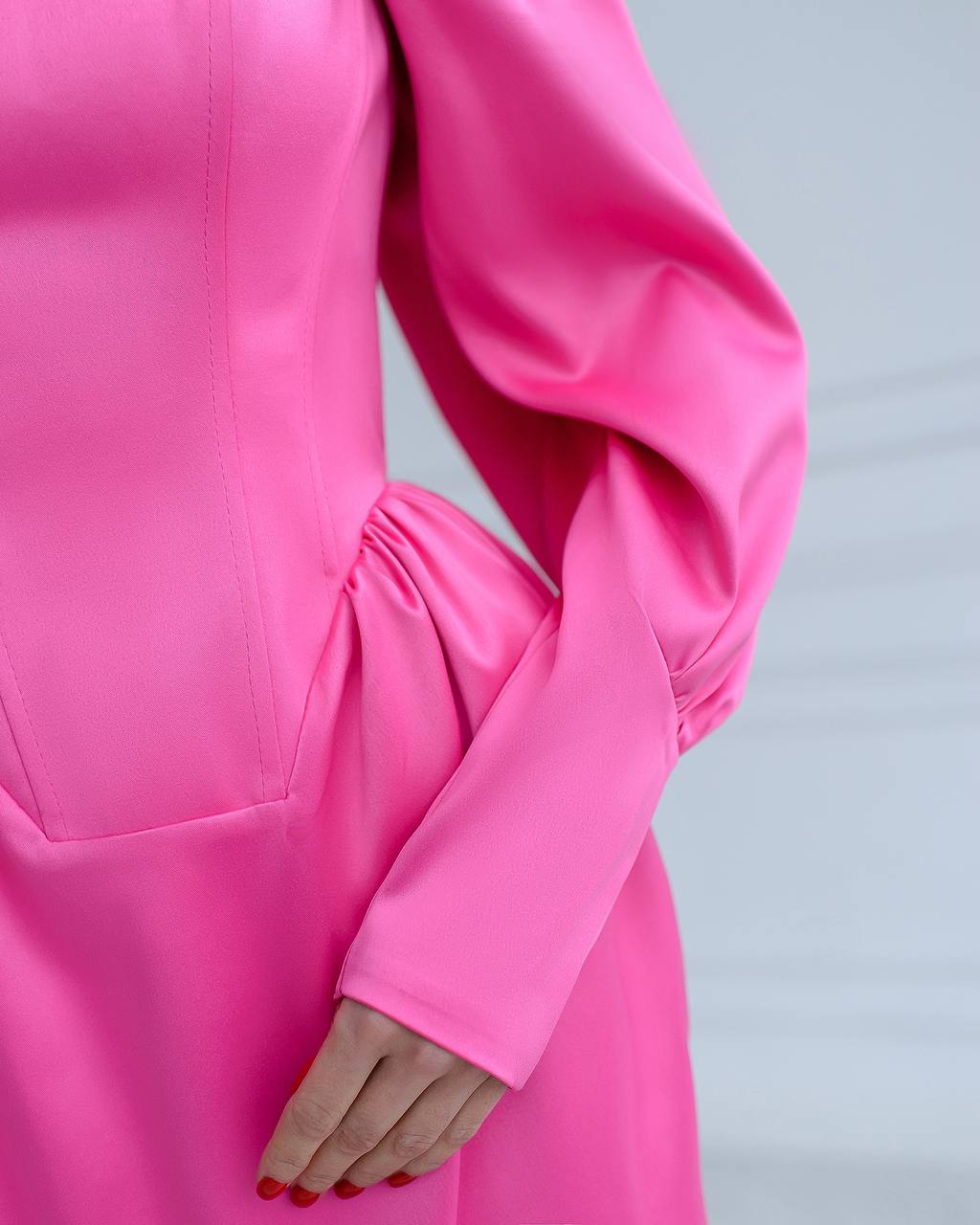 Close-up of a bright pink dress with long sleeves on a light gray background