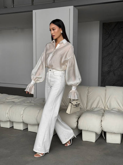 Woman in a stylish outfit standing in a modern room with neutral decor.