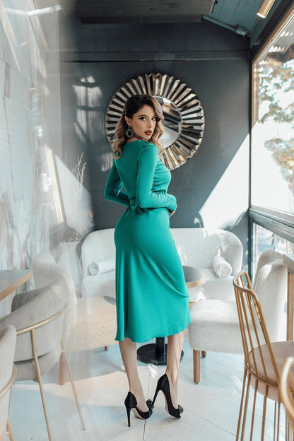 Woman in a teal dress standing in a modern interior setting
