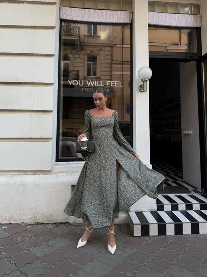 Woman in a long green dress standing outside a store with a reflective window.