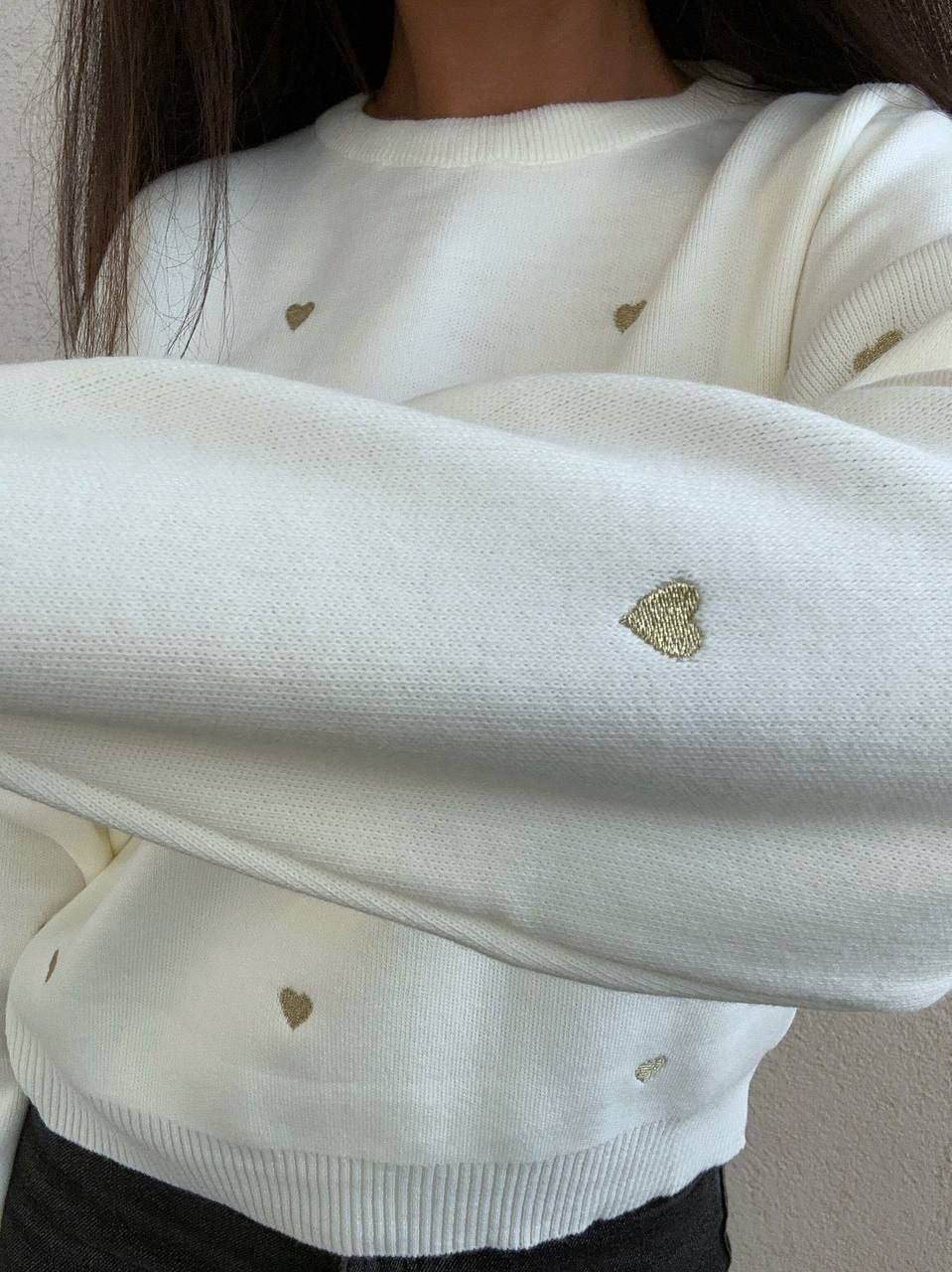 White sweater with gold heart patterns worn by a person.