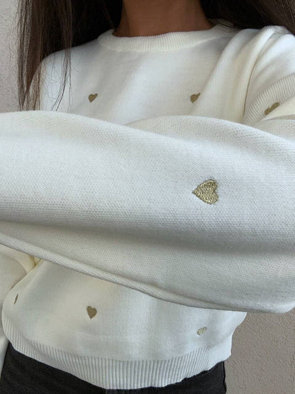 White sweater with gold heart patterns worn by a person.