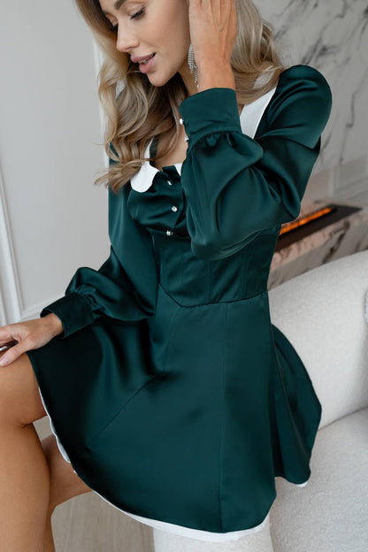 Woman wearing a green dress sitting on a couch.