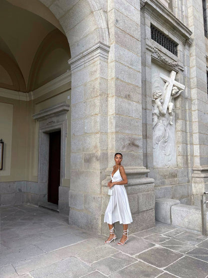 Woman in a white dress standing in front of a stone building with architectural details.