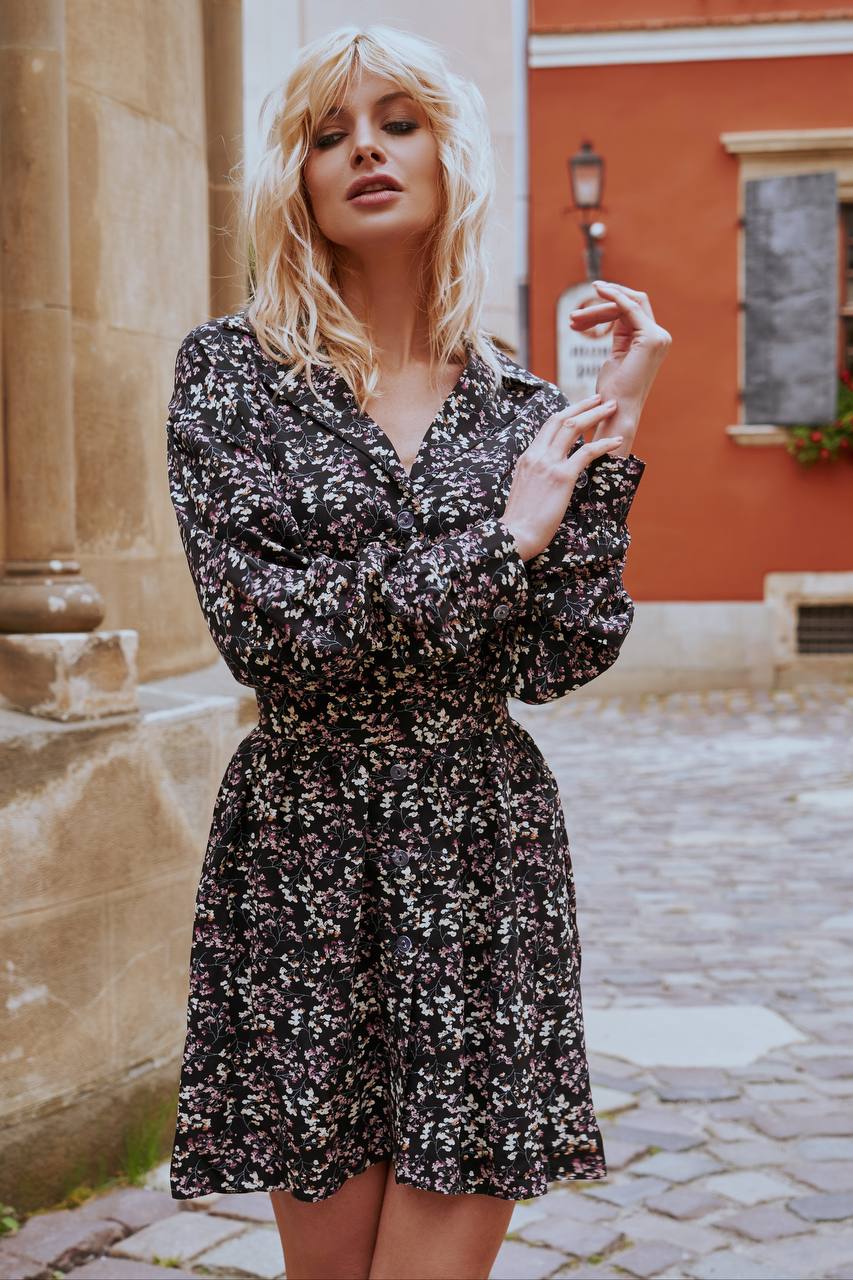 Woman in a floral dress standing on a cobblestone street with a building in the background