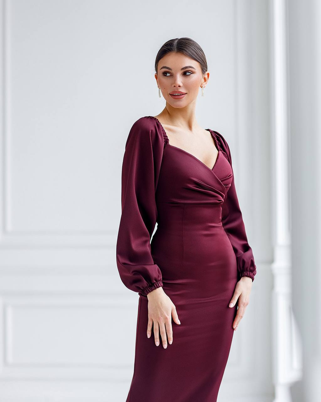 Woman wearing a burgundy dress with long sleeves against a white background