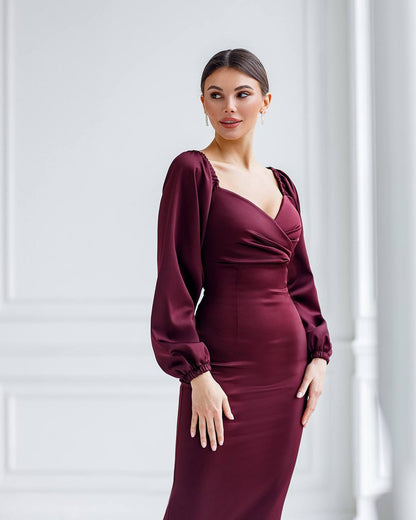 Woman wearing a burgundy dress with long sleeves against a white background