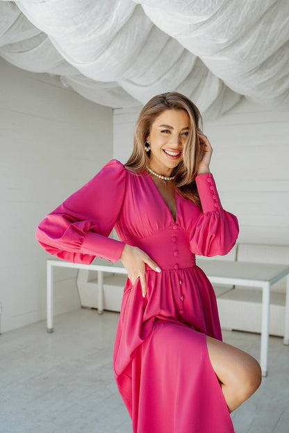 Woman in a pink dress posing in a minimalistic room with white walls and furniture.
